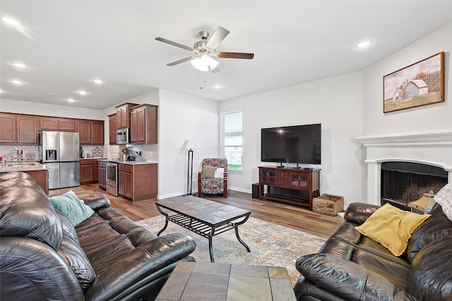 living room featuring sink, ceiling fan, and light hardwood / wood-style floors