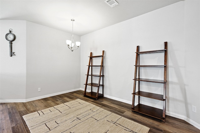 spare room with an inviting chandelier and hardwood / wood-style flooring