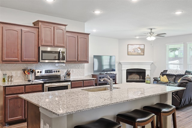 kitchen featuring a breakfast bar area, tasteful backsplash, stainless steel appliances, and a center island with sink