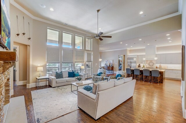 living room featuring ornamental molding, dark hardwood / wood-style flooring, ceiling fan with notable chandelier, and a high ceiling