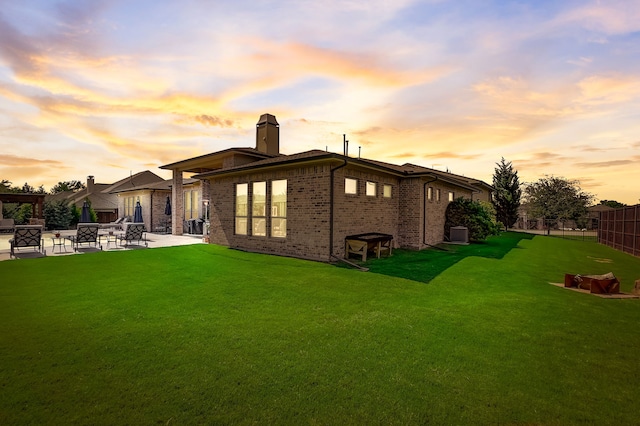 back house at dusk featuring a patio and a yard