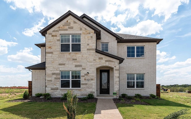 french provincial home featuring a front yard, stone siding, and brick siding