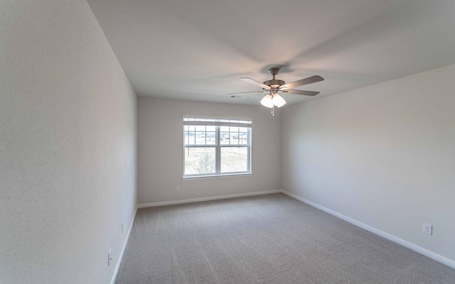 carpeted spare room with a ceiling fan and baseboards