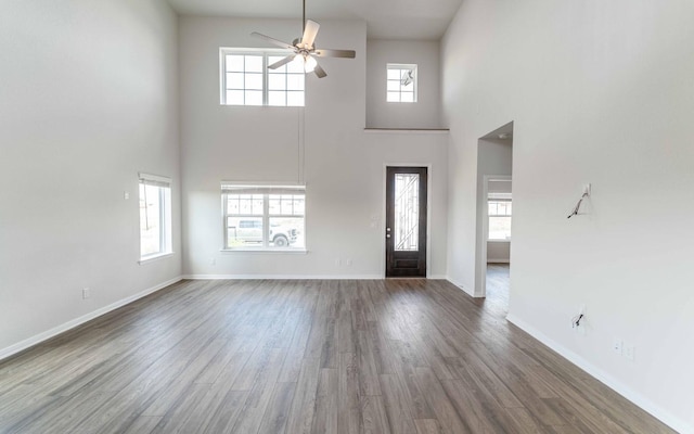 foyer entrance featuring ceiling fan, a towering ceiling, wood finished floors, and baseboards