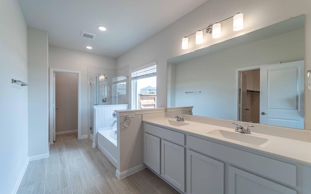 bathroom with a shower stall, a bath, double vanity, baseboards, and recessed lighting