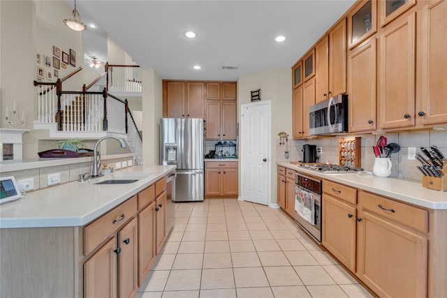 kitchen with appliances with stainless steel finishes, sink, tasteful backsplash, and light tile floors