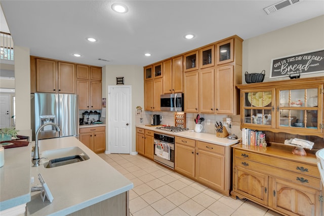 kitchen with backsplash, appliances with stainless steel finishes, sink, and light tile floors