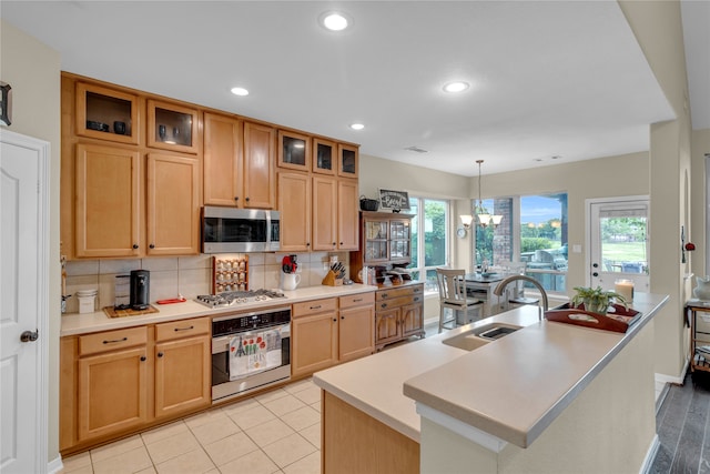 kitchen featuring decorative light fixtures, appliances with stainless steel finishes, sink, and a kitchen island with sink