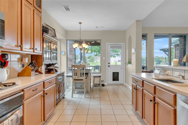 kitchen with a notable chandelier, appliances with stainless steel finishes, tasteful backsplash, and light tile floors