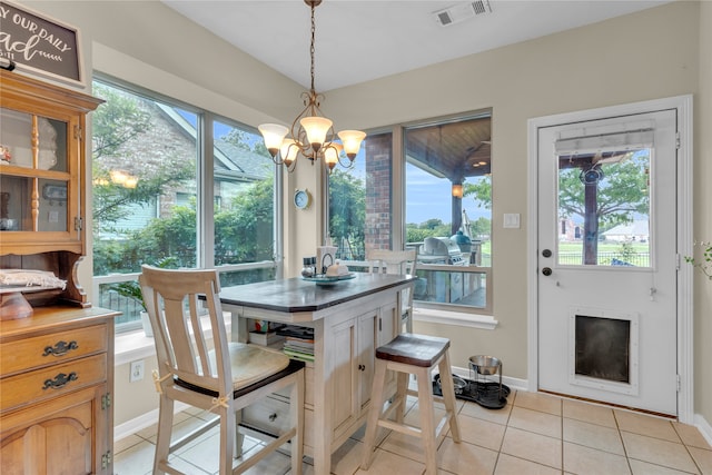 tiled dining room featuring an inviting chandelier and plenty of natural light