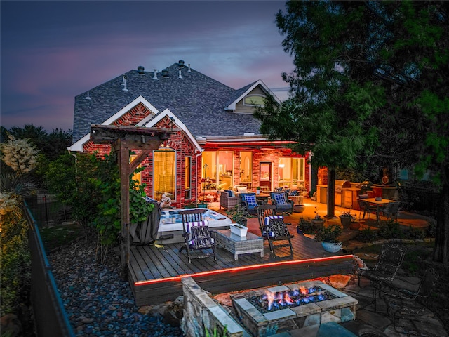 back house at dusk with a deck and an outdoor living space with a fire pit