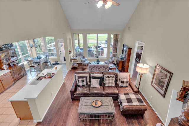 living room with high vaulted ceiling, light hardwood / wood-style floors, plenty of natural light, and ceiling fan