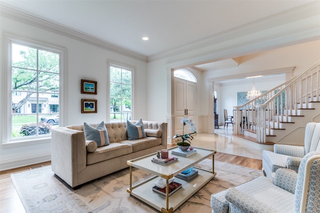 living room with an inviting chandelier, plenty of natural light, ornamental molding, and hardwood / wood-style flooring