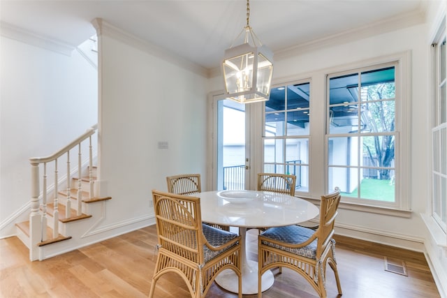 dining room featuring ornamental molding, an inviting chandelier, and light hardwood / wood-style flooring