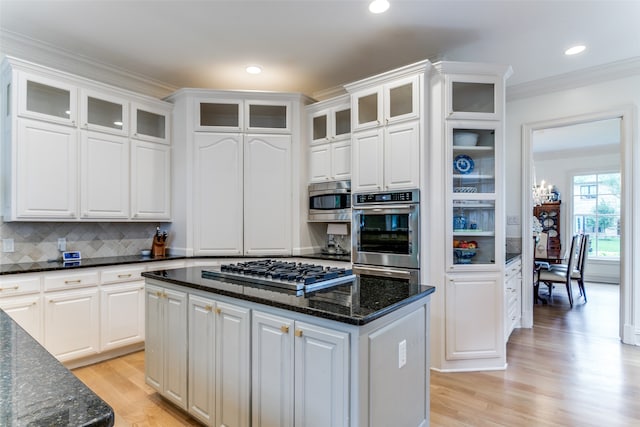 kitchen with tasteful backsplash, stainless steel appliances, light wood-type flooring, a center island, and white cabinets