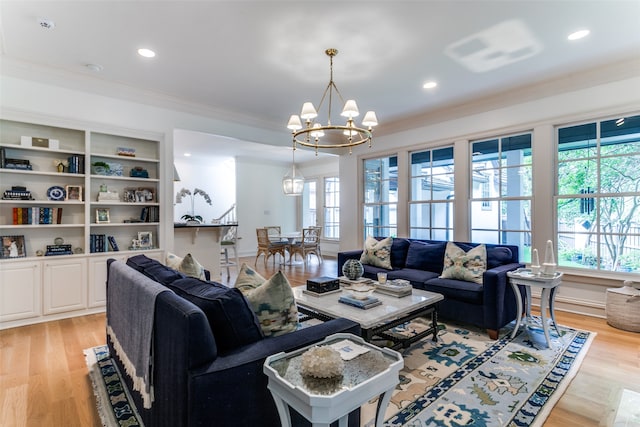 living room with built in features, a chandelier, light hardwood / wood-style flooring, and crown molding