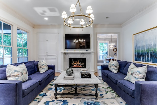 living room with wood-type flooring, a chandelier, a high end fireplace, and crown molding