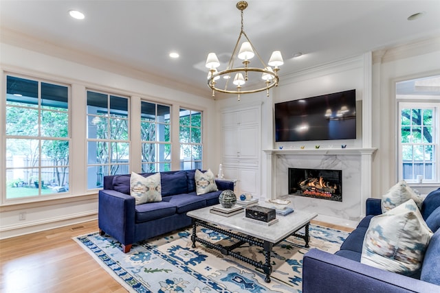 living room featuring a high end fireplace, ornamental molding, hardwood / wood-style flooring, and a notable chandelier