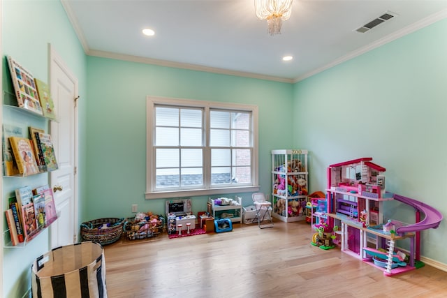 game room featuring a notable chandelier, ornamental molding, and wood-type flooring