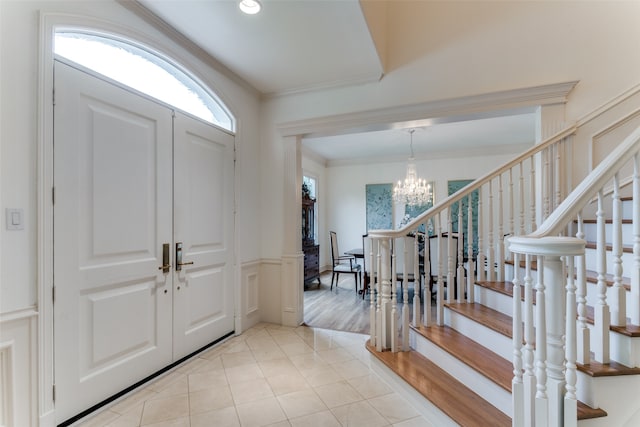 entrance foyer with a notable chandelier, ornamental molding, and light hardwood / wood-style floors