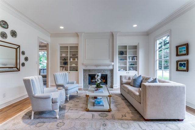 living room featuring ornamental molding, built in shelves, and light hardwood / wood-style flooring