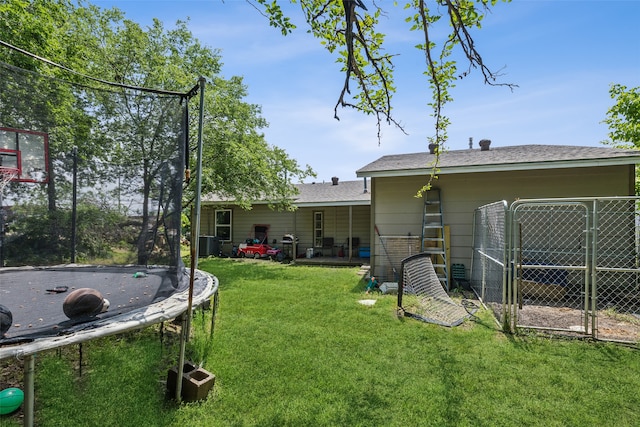 view of yard featuring a trampoline and central AC