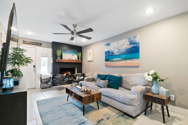 living room featuring ceiling fan, a large fireplace, and light tile patterned floors