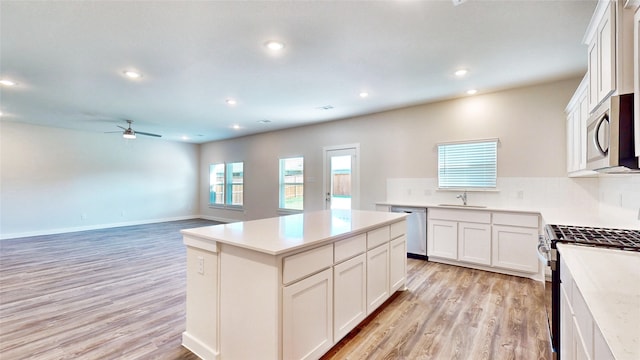 kitchen with a kitchen island, light hardwood / wood-style flooring, stainless steel appliances, ceiling fan, and white cabinets