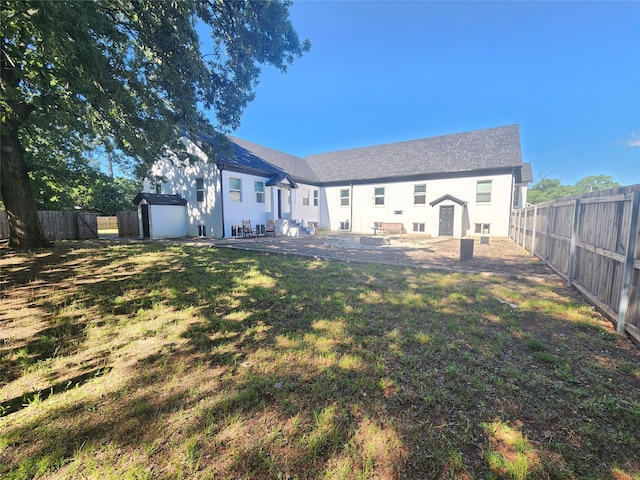 rear view of property with a patio, a lawn, and a storage unit