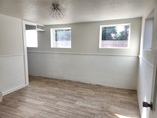 empty room featuring light wood-type flooring and a healthy amount of sunlight