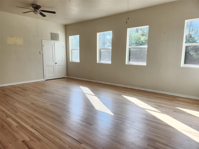 spare room with plenty of natural light, light wood-type flooring, and ceiling fan