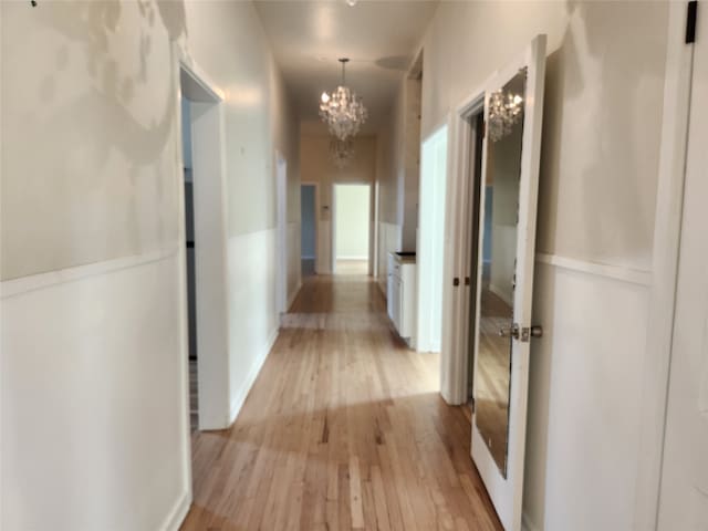 hallway featuring a notable chandelier and light wood-type flooring