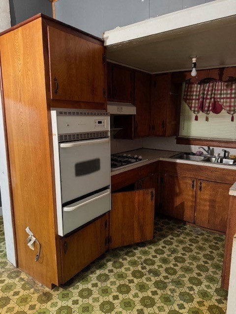 kitchen featuring extractor fan, black gas cooktop, sink, dark tile floors, and double oven