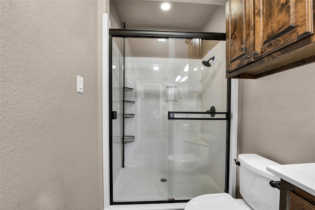 bathroom featuring walk in shower, toilet, and vanity