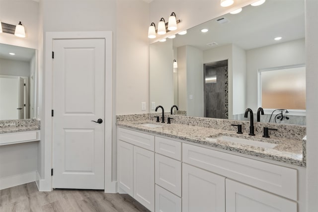 bathroom with double vanity and wood-type flooring