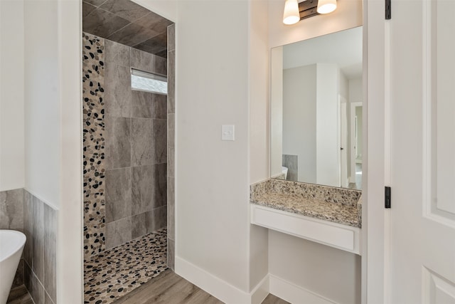 bathroom featuring tile walls, separate shower and tub, wood-type flooring, and vanity