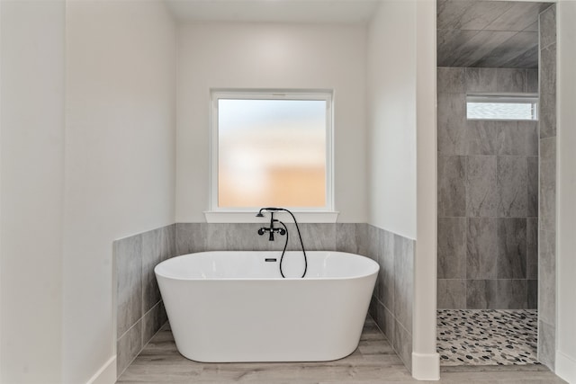 bathroom featuring tiled shower, tile walls, and a wealth of natural light