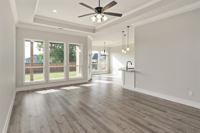 spare room with ornamental molding, ceiling fan with notable chandelier, hardwood / wood-style flooring, and a tray ceiling