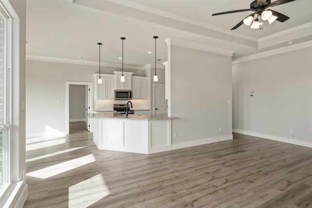 kitchen with tasteful backsplash, ceiling fan, hanging light fixtures, white cabinets, and light hardwood / wood-style floors