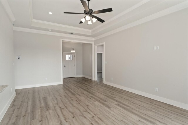 spare room featuring light hardwood / wood-style floors, ceiling fan, crown molding, and a tray ceiling