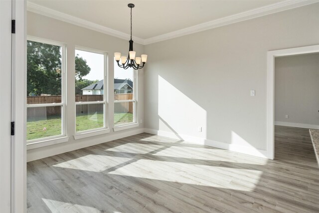 unfurnished dining area featuring ornamental molding, light wood-type flooring, and a chandelier