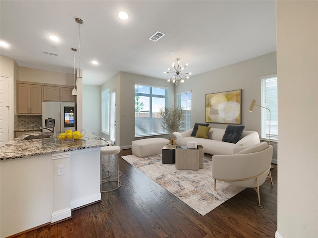 living room with dark hardwood / wood-style flooring, a chandelier, and sink