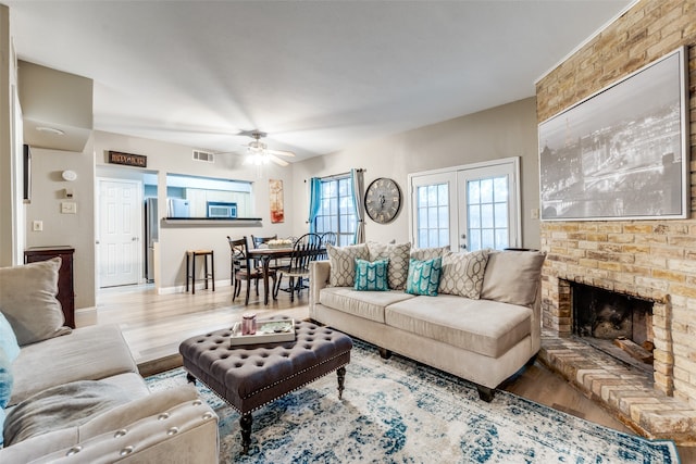 living room featuring ceiling fan, french doors, a fireplace, and hardwood / wood-style flooring