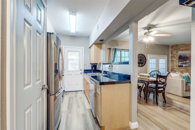 kitchen with appliances with stainless steel finishes, sink, ceiling fan, and light hardwood / wood-style floors