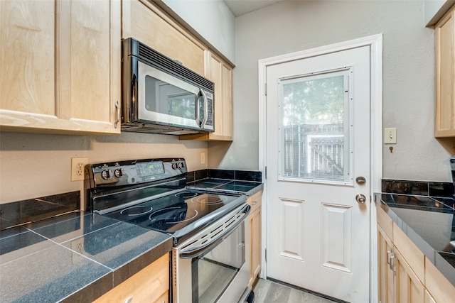 kitchen featuring stainless steel appliances, light brown cabinetry, and wood-type flooring