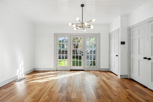 unfurnished room featuring light hardwood / wood-style floors, crown molding, and an inviting chandelier