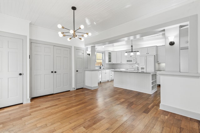 kitchen featuring hanging light fixtures, ornamental molding, light hardwood / wood-style flooring, and white cabinetry