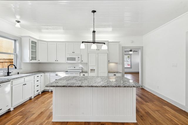 kitchen with white appliances, a kitchen island, backsplash, sink, and ornamental molding