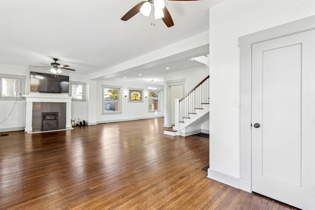 unfurnished living room with dark wood-type flooring, ceiling fan, and a tile fireplace