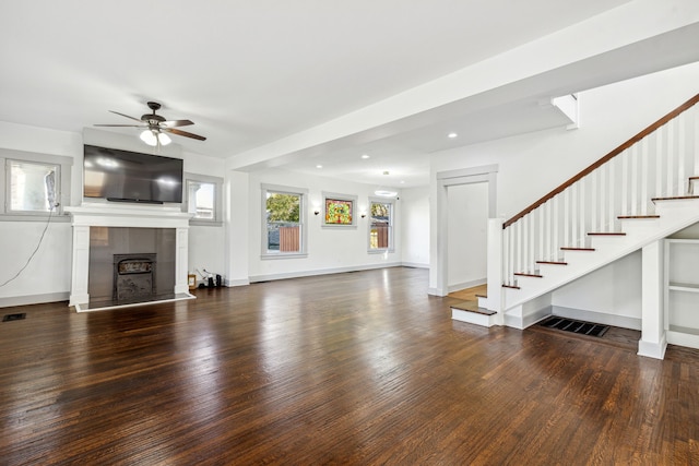 unfurnished living room with dark wood-type flooring, a tiled fireplace, and ceiling fan